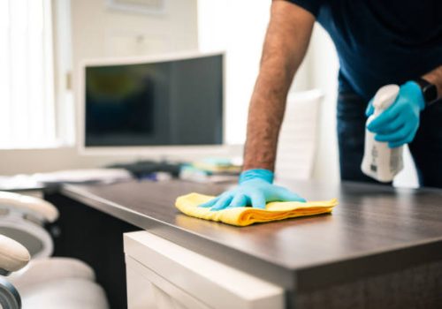 man disinfecting an office desk