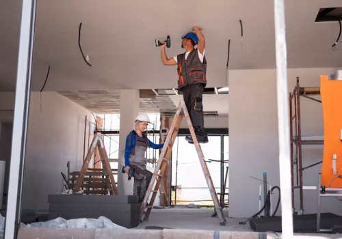 full shot man woman standing ladder ceiling & wall maintenance